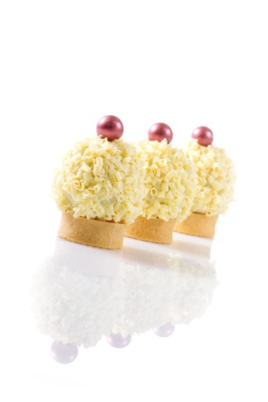 Tartelettes, verziert mit gugelförmig angerichteten Schokoladenraspeln aus weißer Schokolade und einer glänzenden Perle oben drauf. 