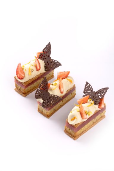 Lace Butterfly Dekor aus Zartbitterschokolade angerichtet auf kleinen Stückchen in rechteckiger Form mit Erdbeeren.
